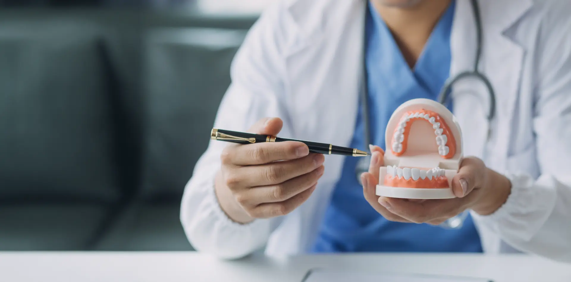Dentist using a dental model to explain a tooth extraction to a patient